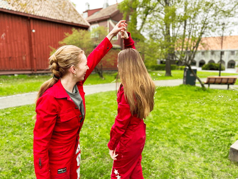 To russejenter som holder hender på en plen.